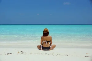 Woman sitting on a beach whilst on a wellness retreat