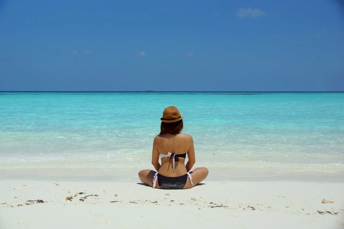 Woman sitting on a beach whilst on a wellness retreat