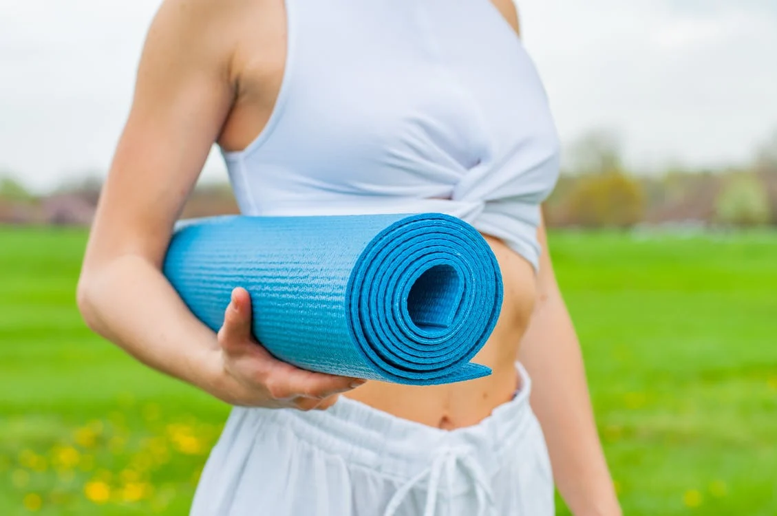 Woman holding yoga mat.